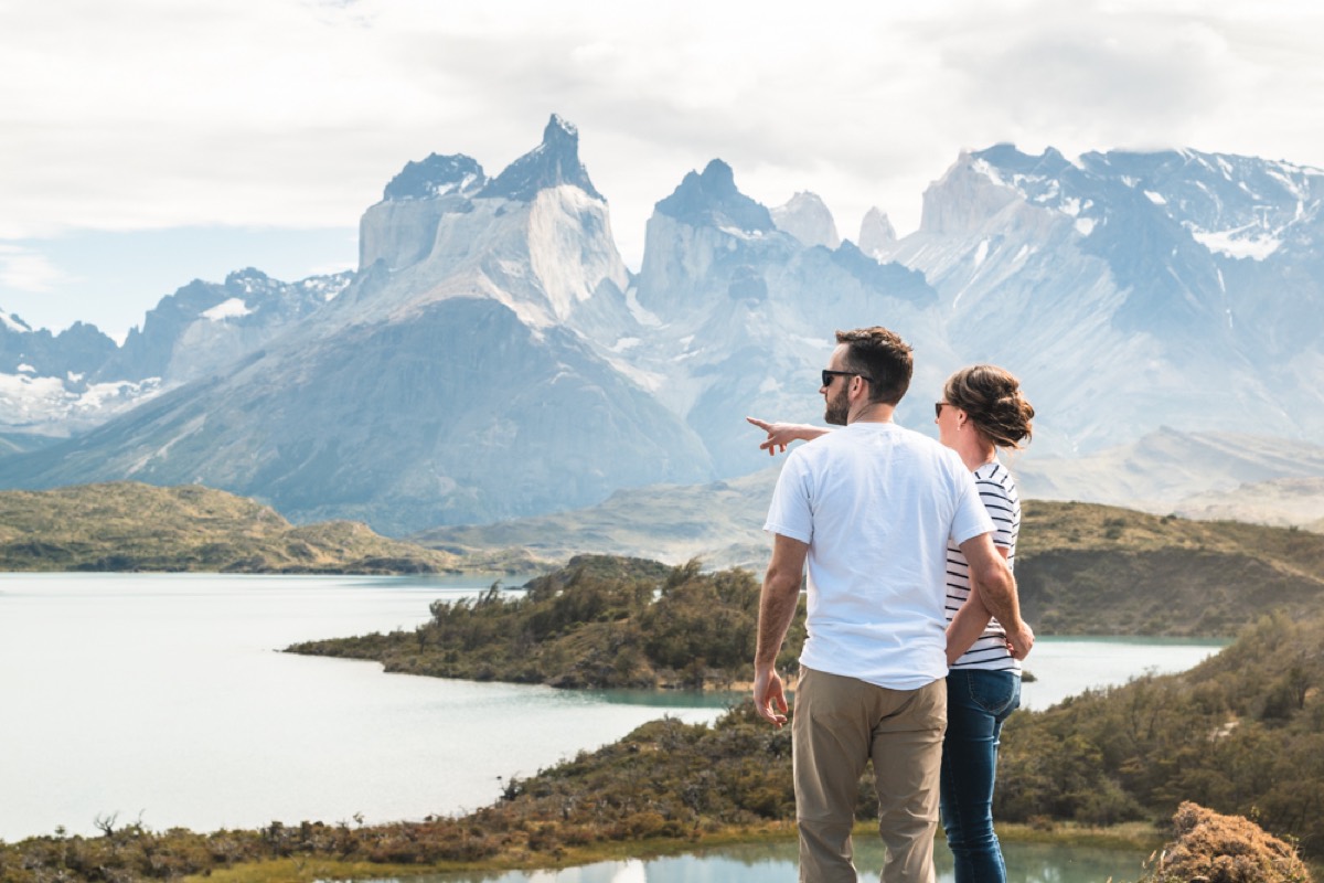 A couple looking out over a turquoise lake to the Cuernos del Paine on a full-day tour