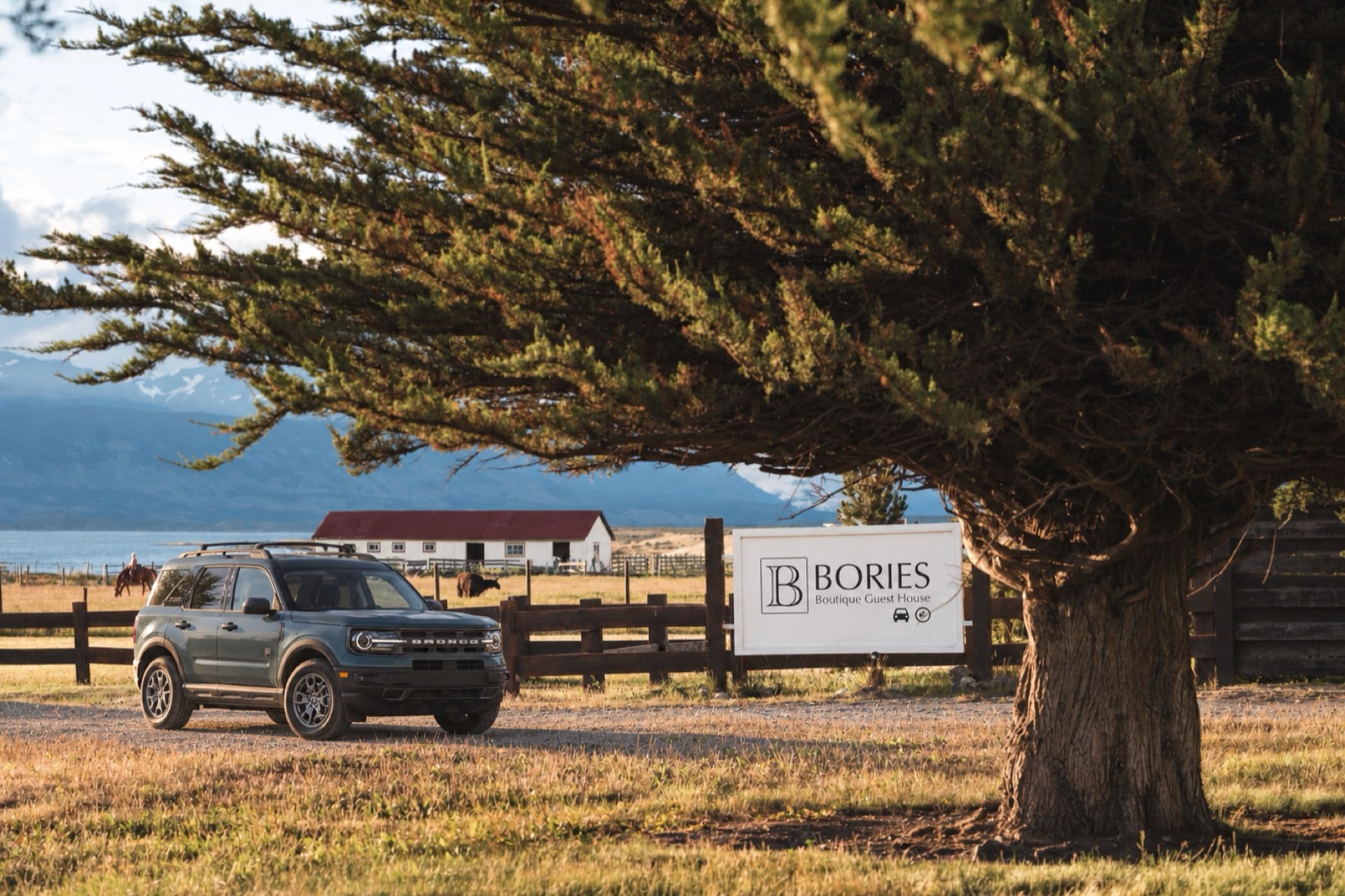 A Ford Bronco SUV by the Bories sign, with the fjord behind