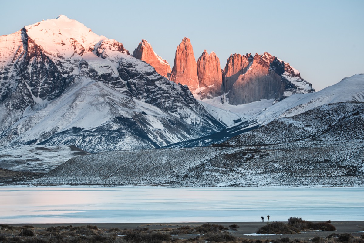 The Torres del Paine massif under winter snow at sunrise, with alpenglow on the towers