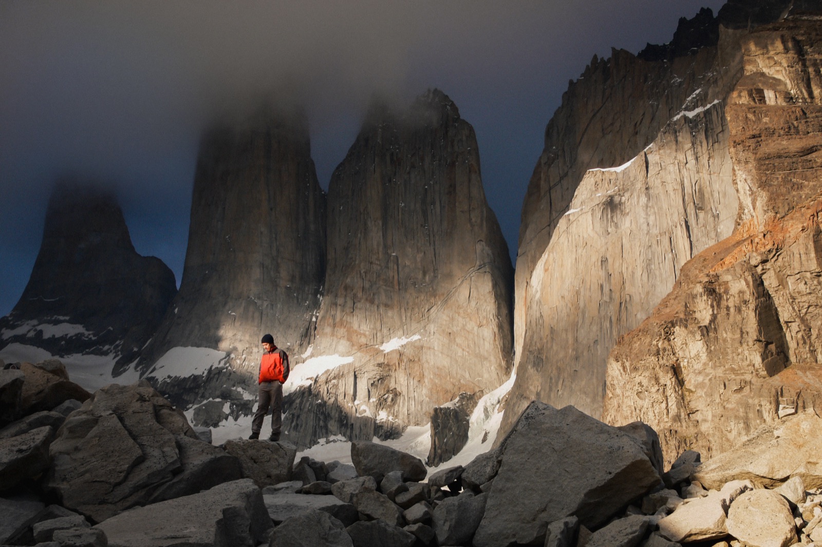 Two hikers at the glacial lagoon below the three granite towers of Torres del Paine