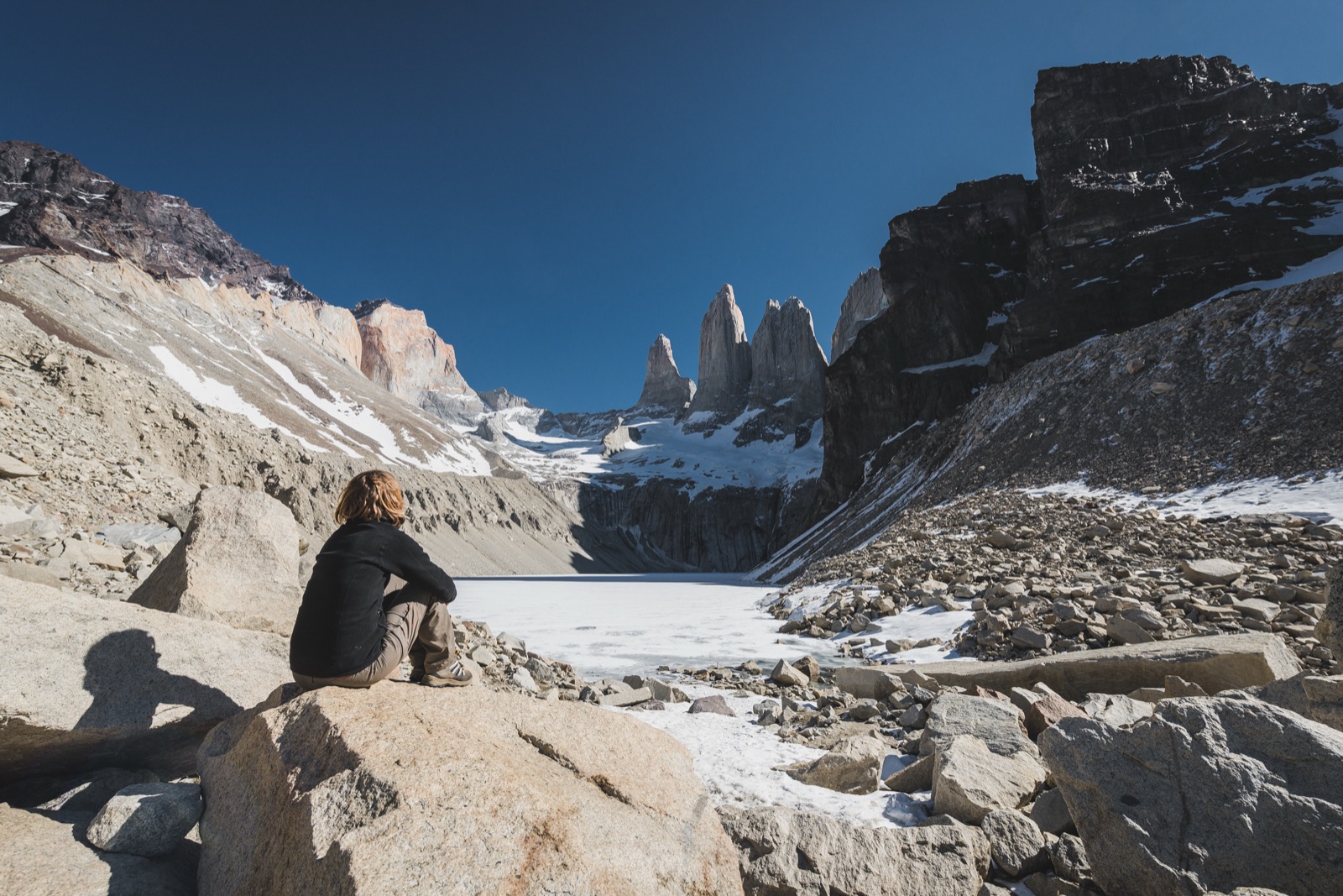 Two hikers at the glacial lagoon below the three granite towers of Torres del Paine