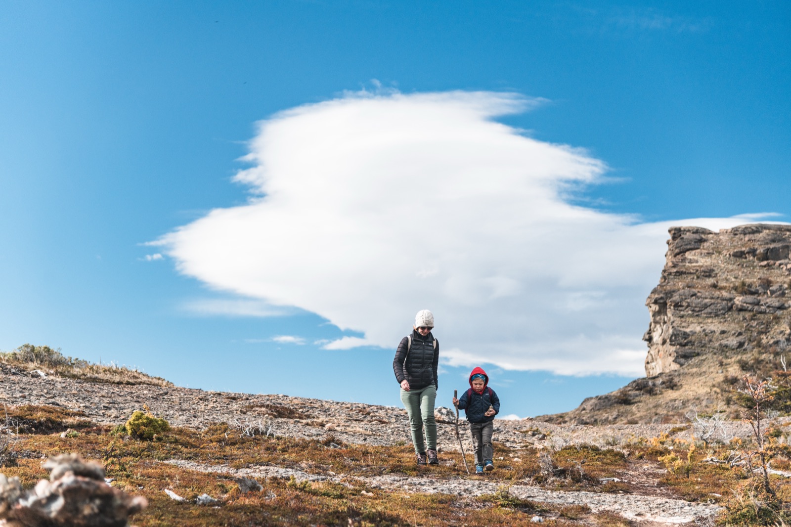 A lone hiker on a cliff edge above the valley and fjord near Puerto Natales