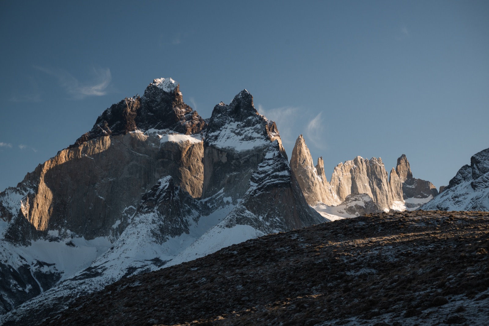 A couple looking out over a turquoise lake to the Cuernos del Paine