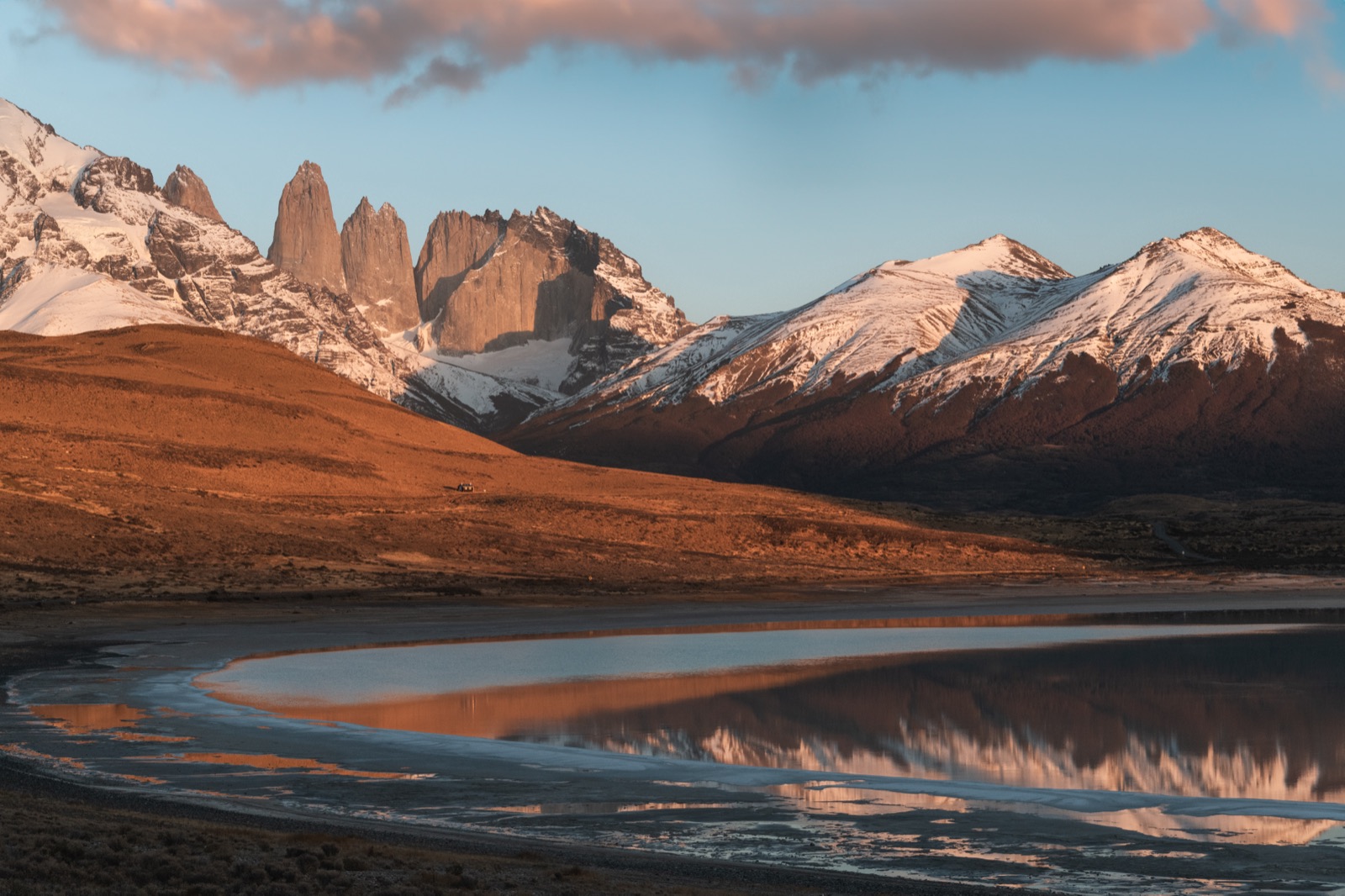 A couple looking out over a turquoise lake to the Cuernos del Paine on a full-day tour