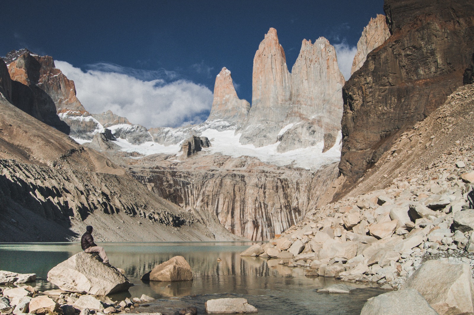 Two hikers at the glacial lagoon below the three granite towers of Torres del Paine