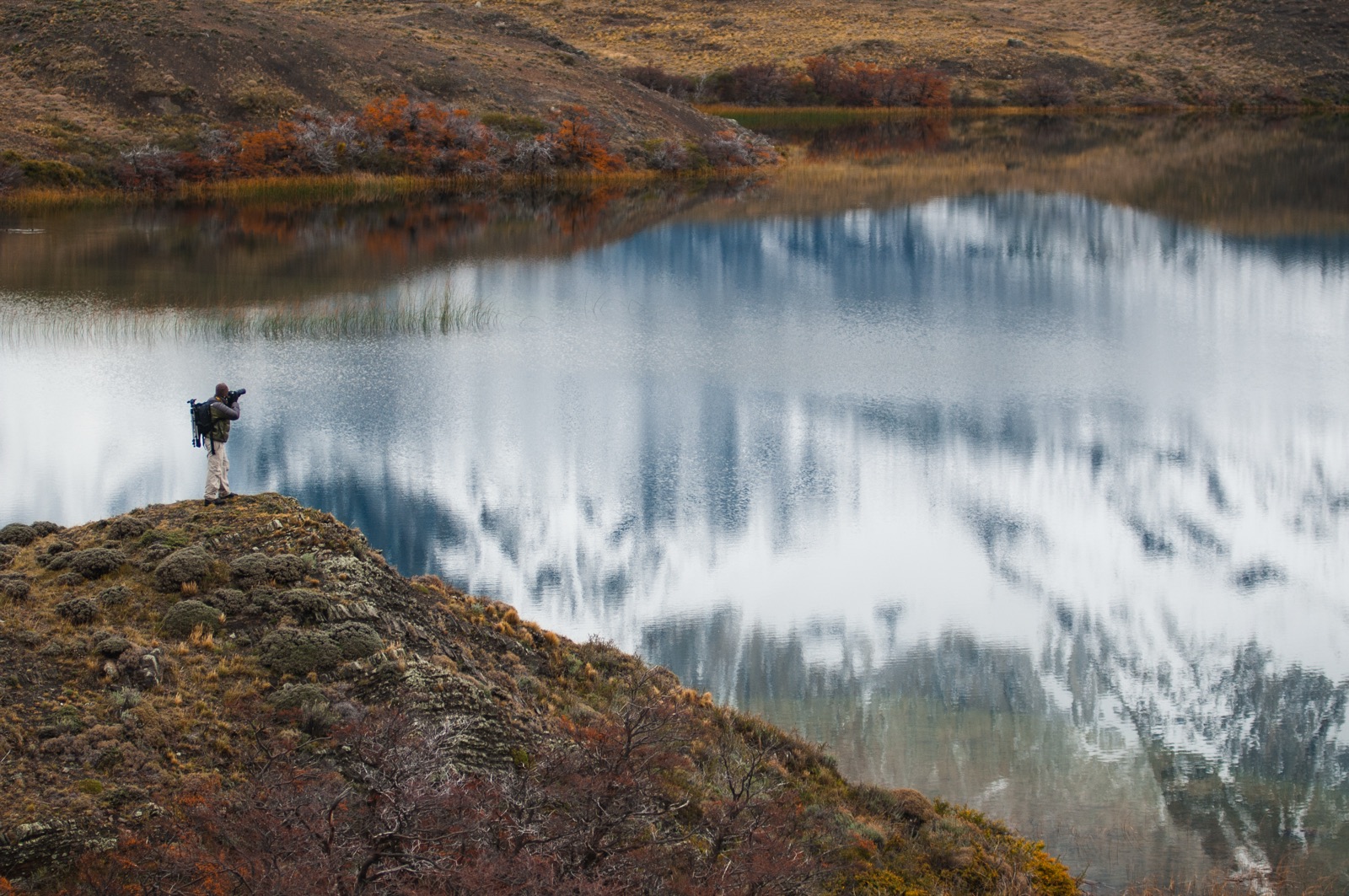 A couple looking out over a turquoise lake to the Cuernos del Paine