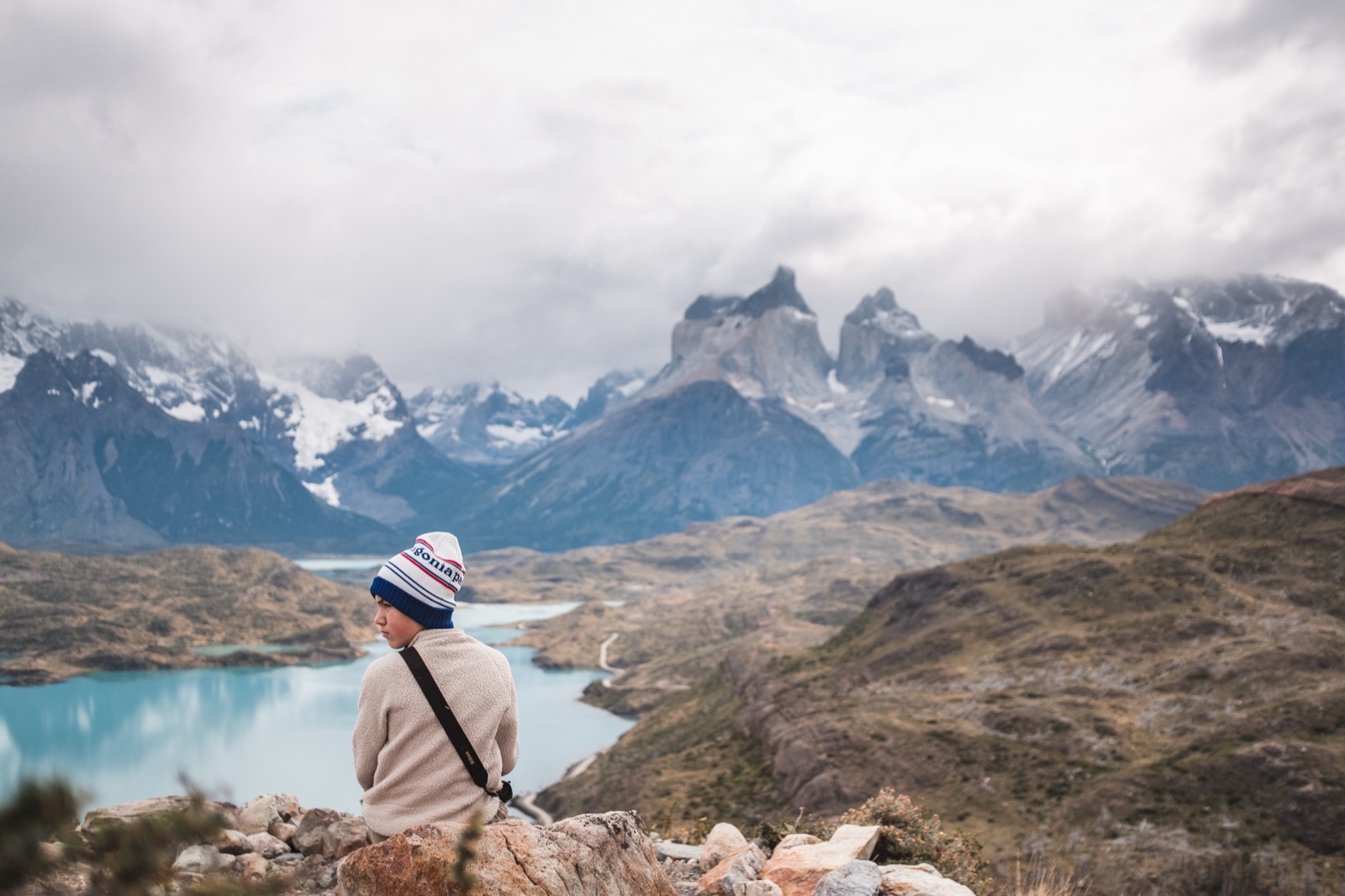 A couple looking out over a turquoise lake to the Cuernos del Paine