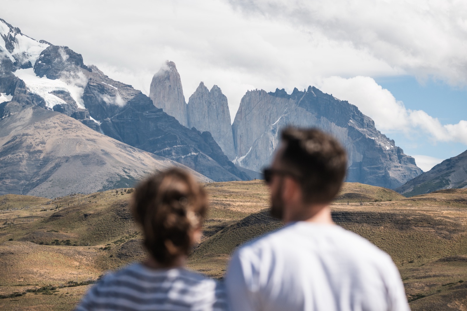 A couple looking out over a turquoise lake to the Cuernos del Paine on a full-day tour