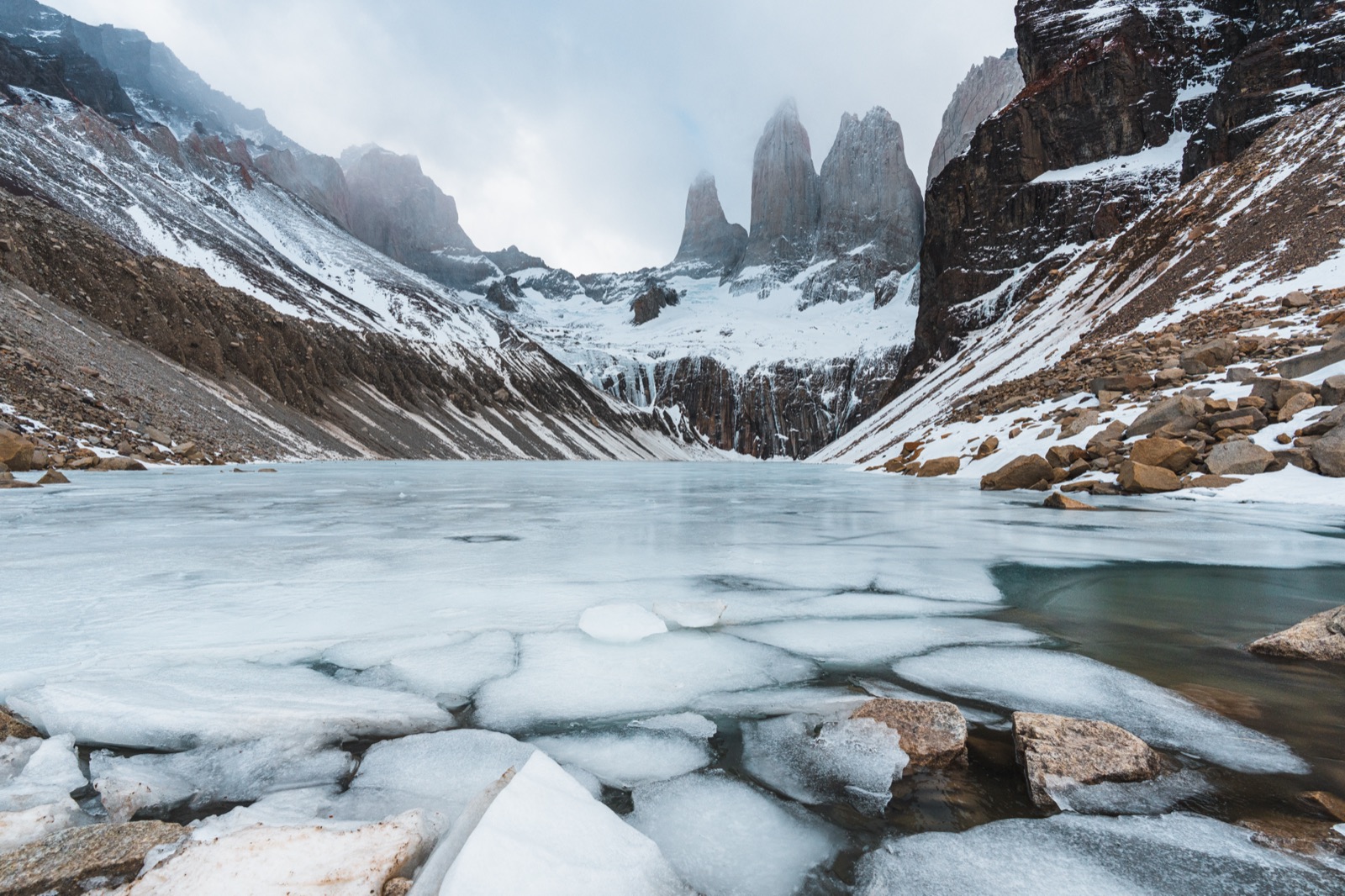 Two hikers at the glacial lagoon below the three granite towers of Torres del Paine