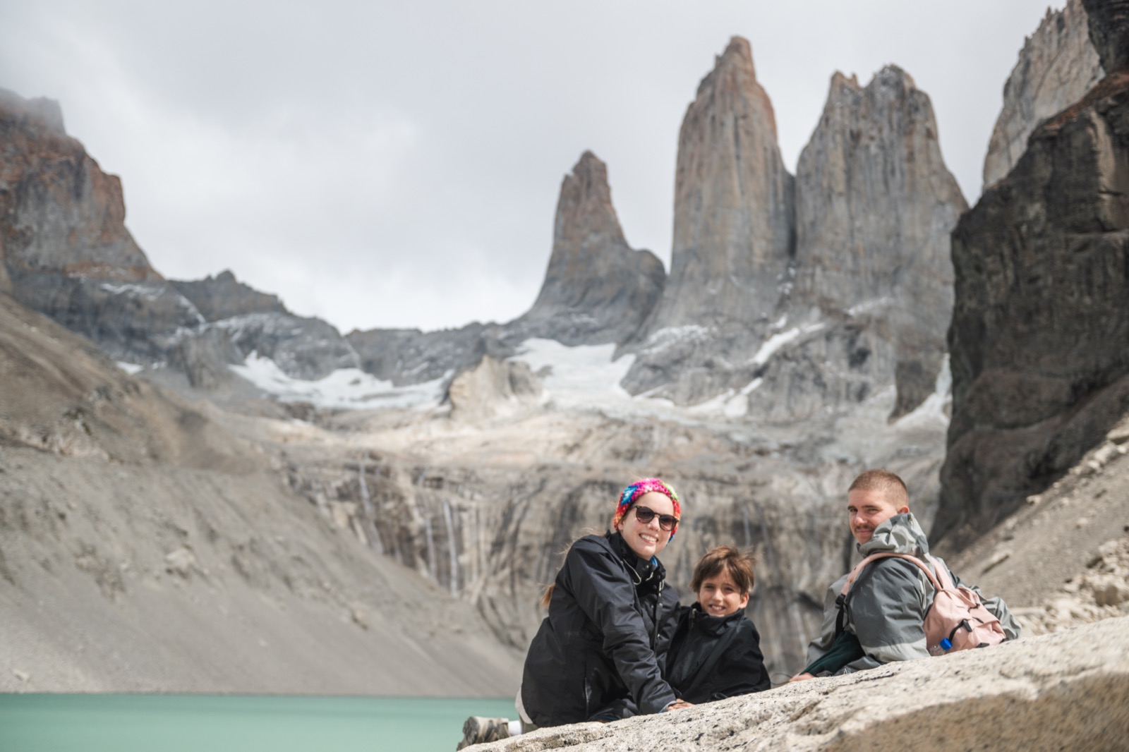 Two hikers at the glacial lagoon below the three granite towers of Torres del Paine