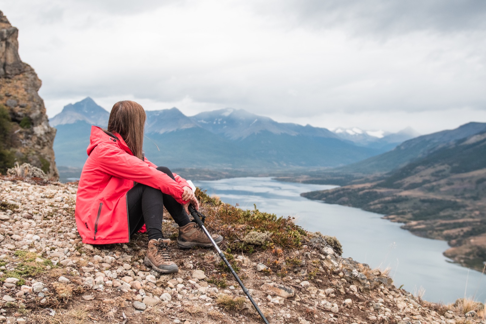 A lone hiker on a cliff edge above the valley and fjord near Puerto Natales