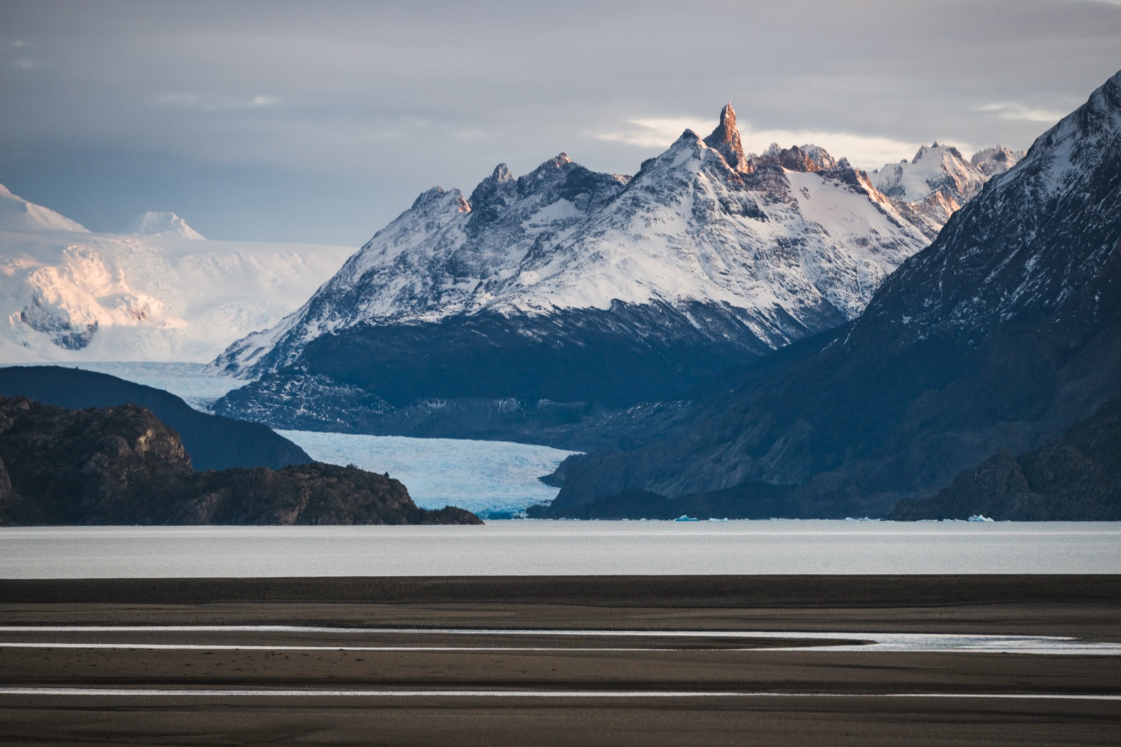 The blue ice wall of Grey Glacier meeting a rocky ridge, seen from the water
